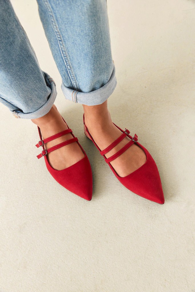 woman in jeans with a rolled-up hem, wearing sling-back red pointed shoes.